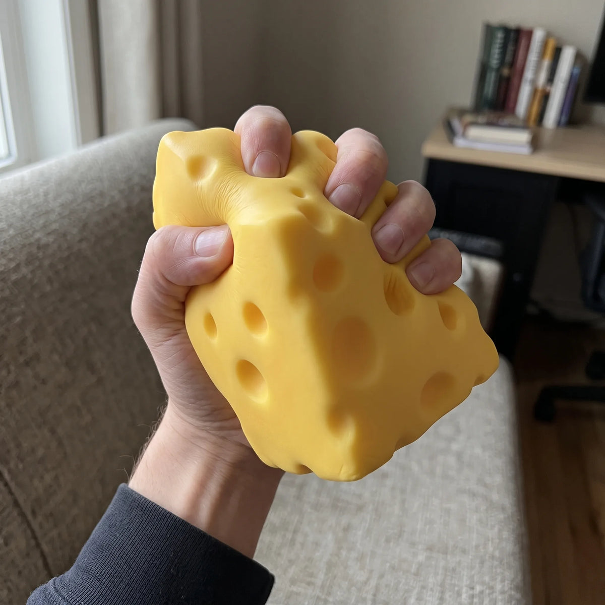 Big cheese squishy squeezed in one hand in a living room