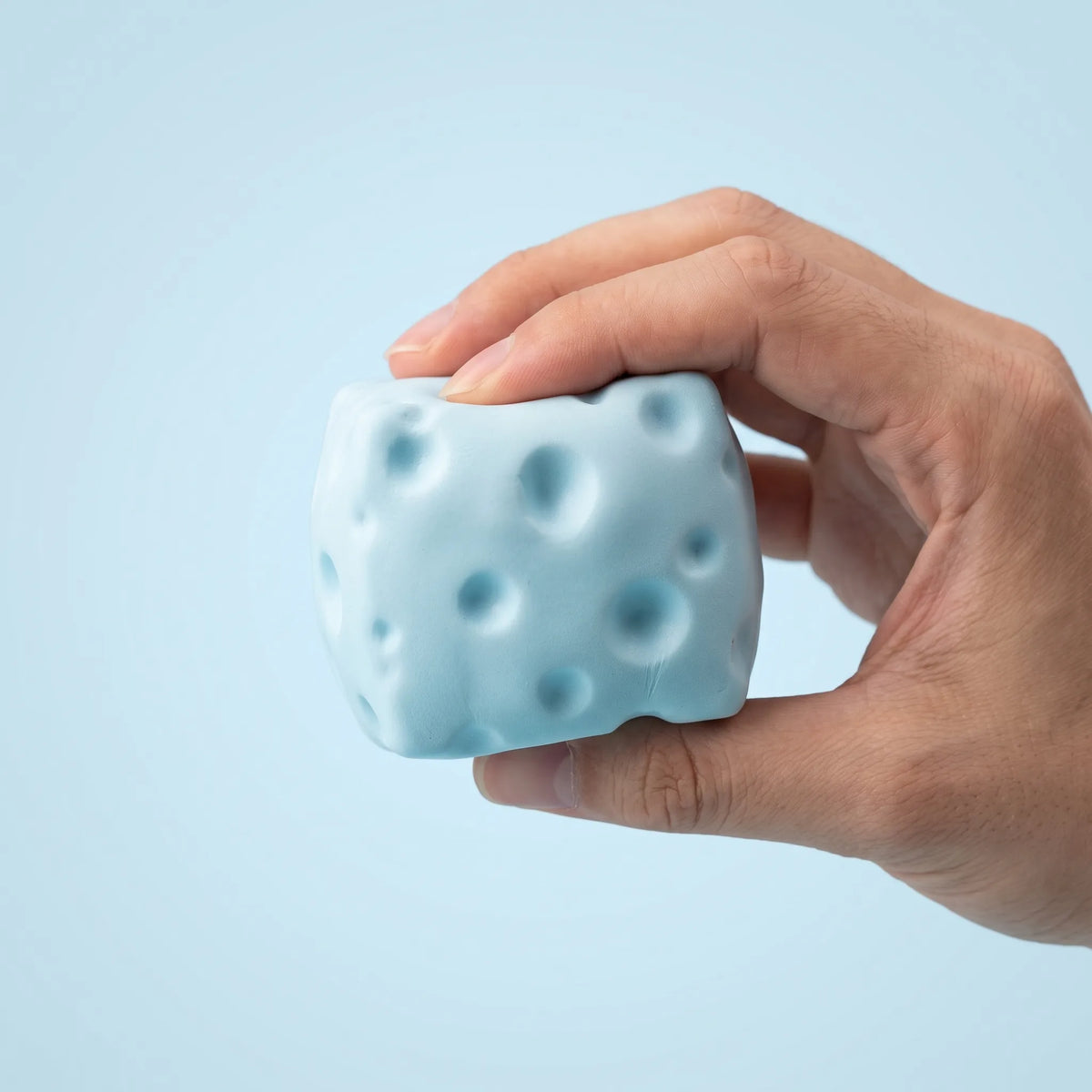 Blue cheese squishy block gripped in a closed fist