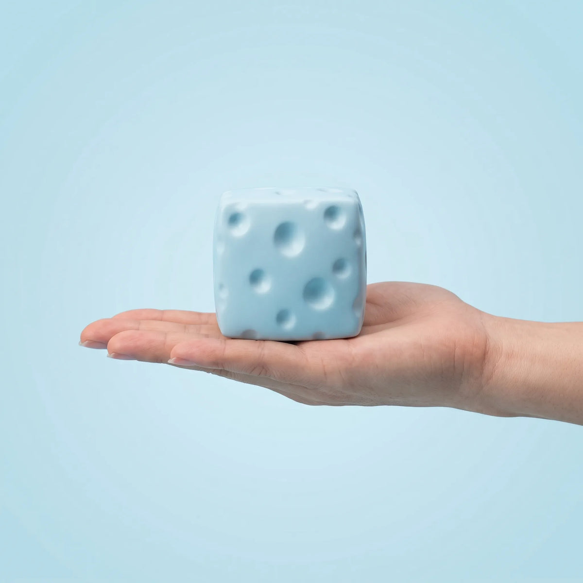 Blue cheese squishy block held in an open hand to show its 6 cm size