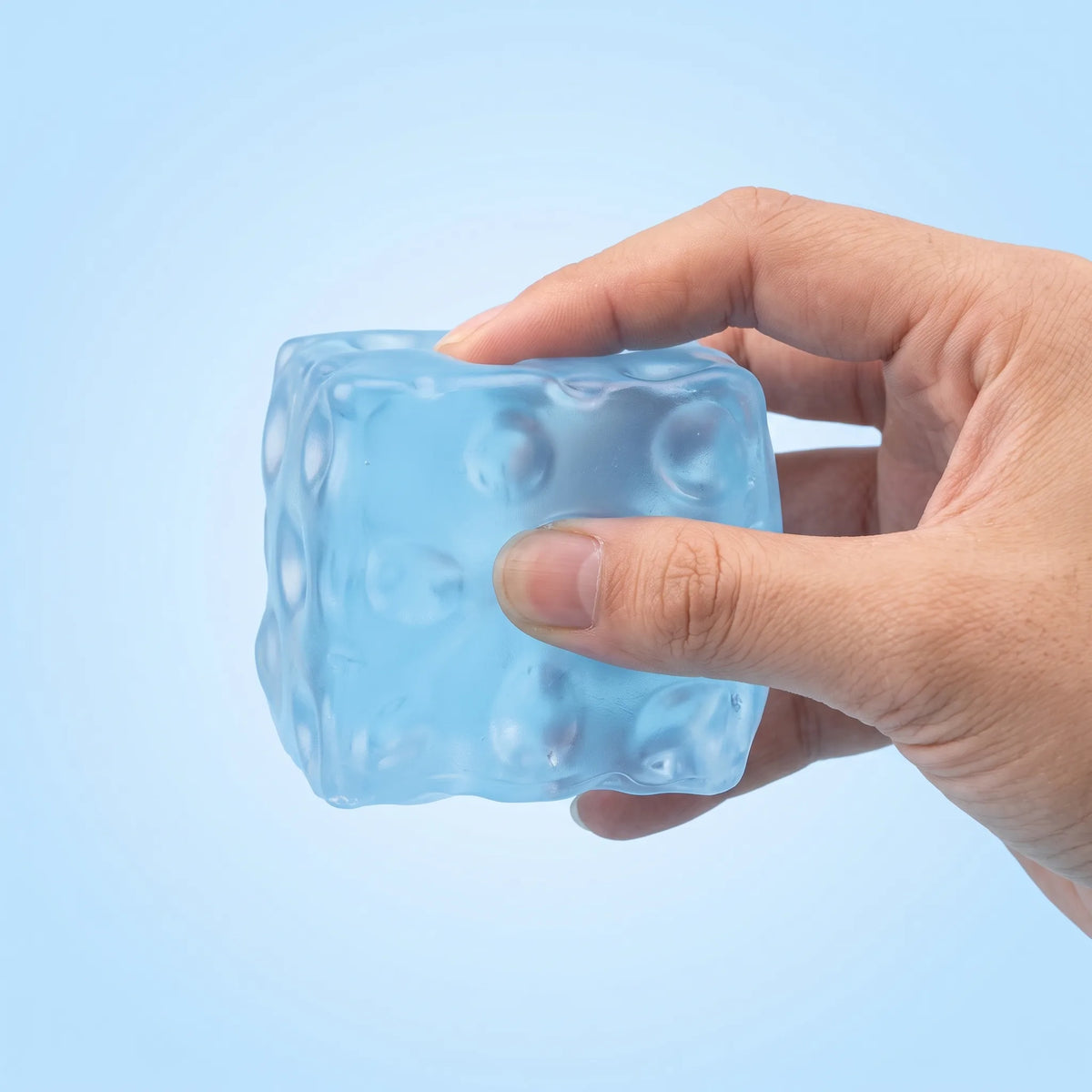 Hand squeezing the clear blue cheese squishy cube evenly