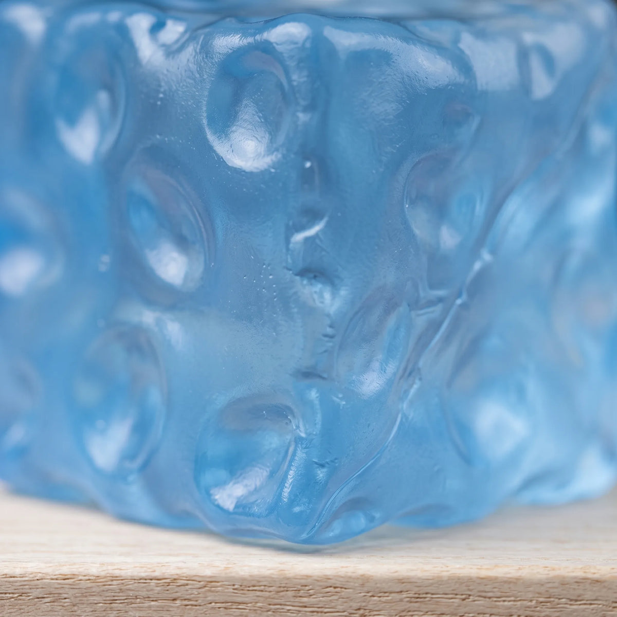Macro view of the moulded holes catching light in the clear blue cheese squishy cube