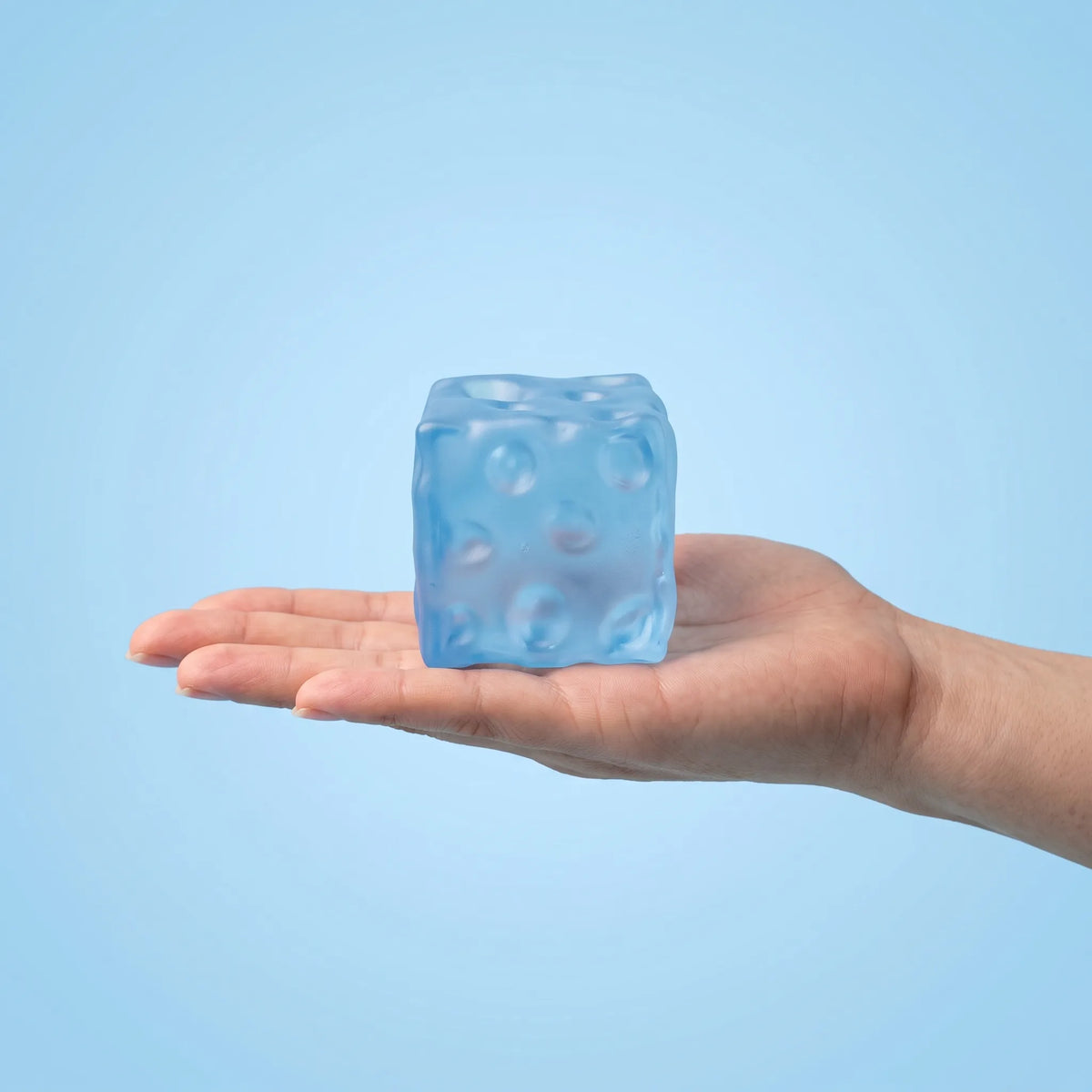 Clear blue cheese squishy cube held in an open hand to show its size