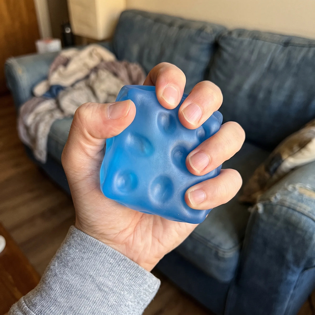 Adult hand pressing the clear blue cheese squishy cube flat