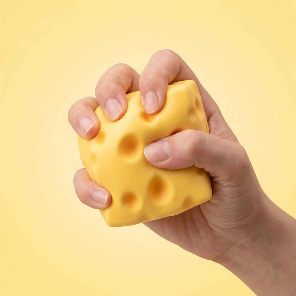 Hand squeezing the cheese squishy toy to show how far it compresses