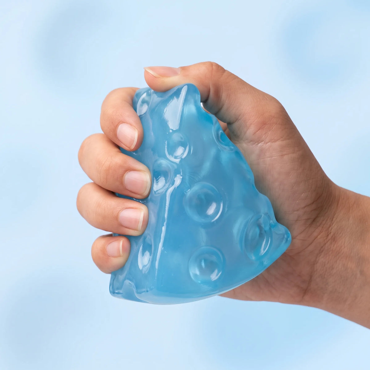 Fingers squeezing the ice blue cheese squishy wedge until the point folds