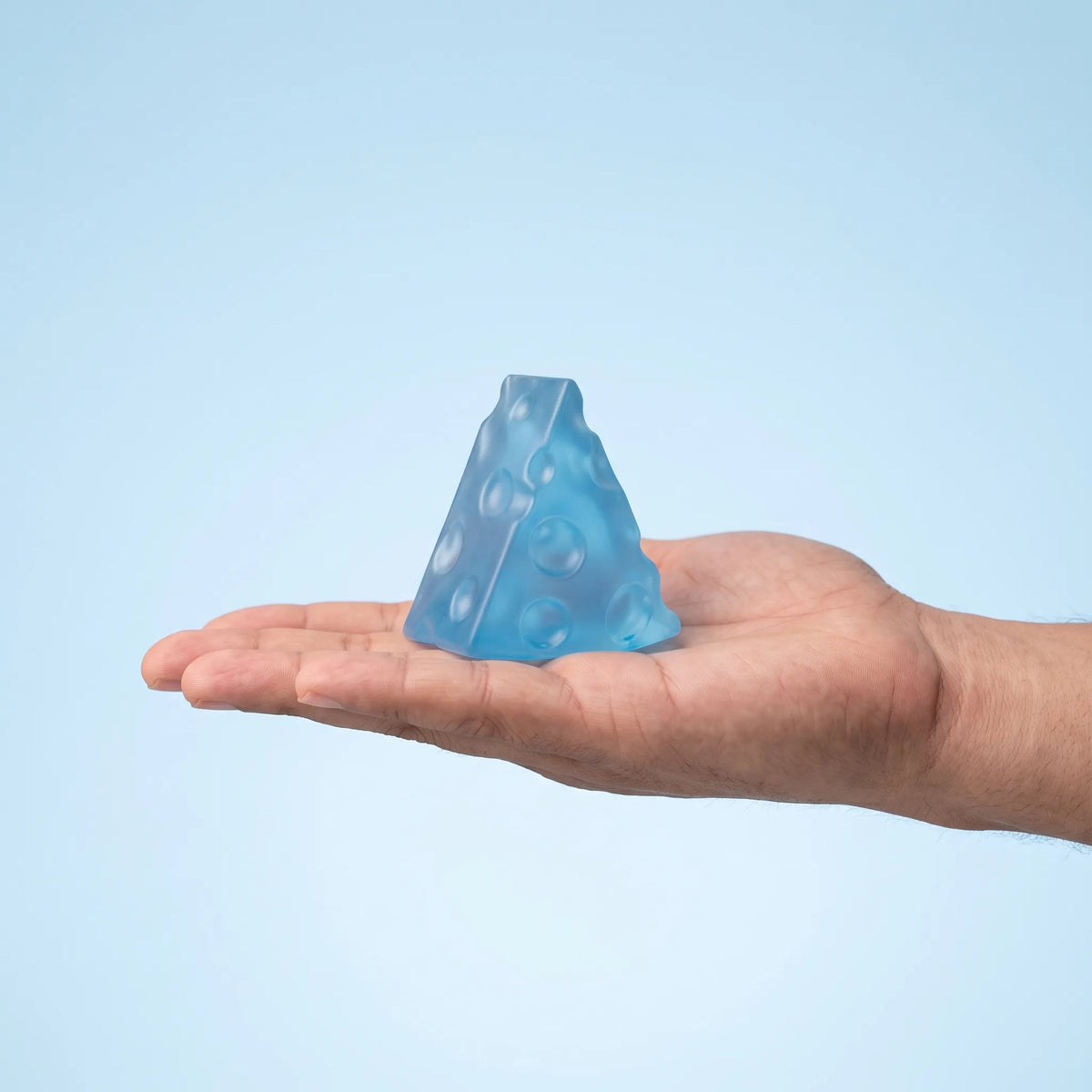 Ice blue cheese squishy wedge held in an open hand to show its 5 cm size