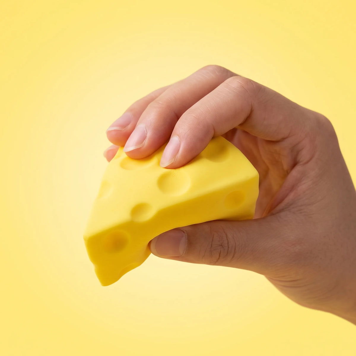 Hand squeezing a wedge from the cheese squishy set of six