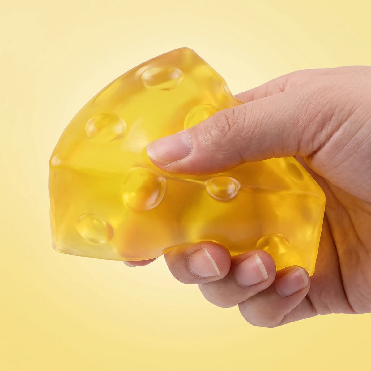Hand squeezing the clear cheese squishy wedge so it folds along its thin edge