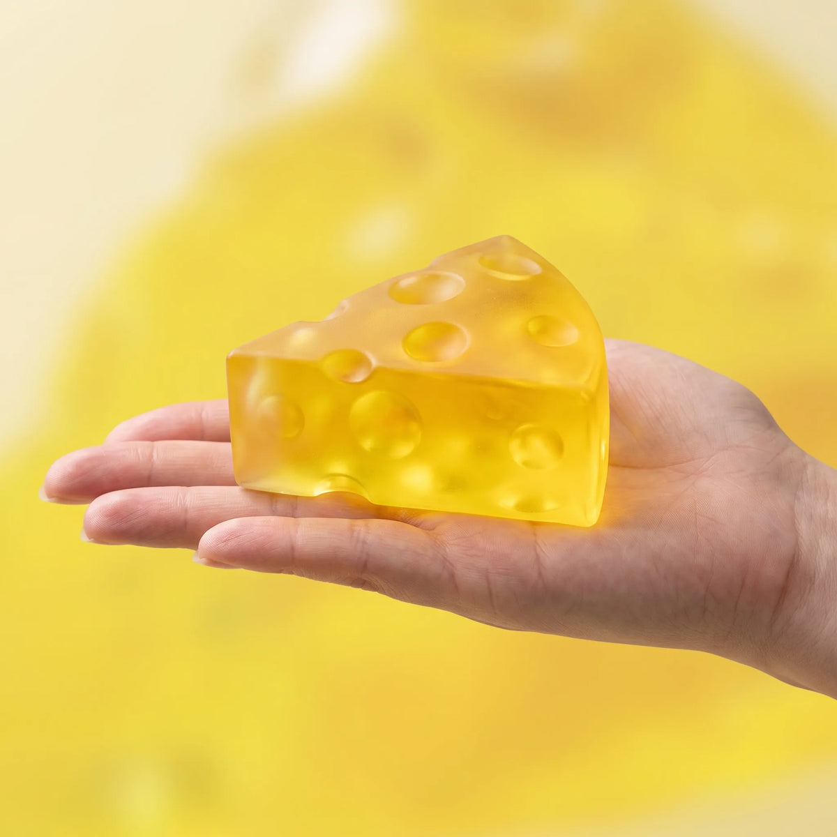 Clear cheese squishy wedge held in an open hand to show its 6 cm size