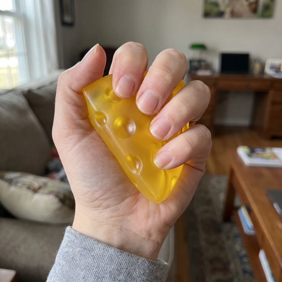 Adult hand pressing the clear cheese squishy wedge flat between fingers