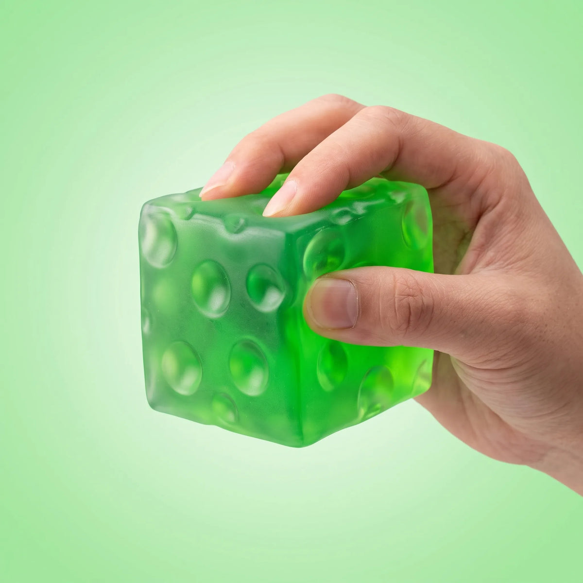 Hand squeezing the clear green cheese squishy cube