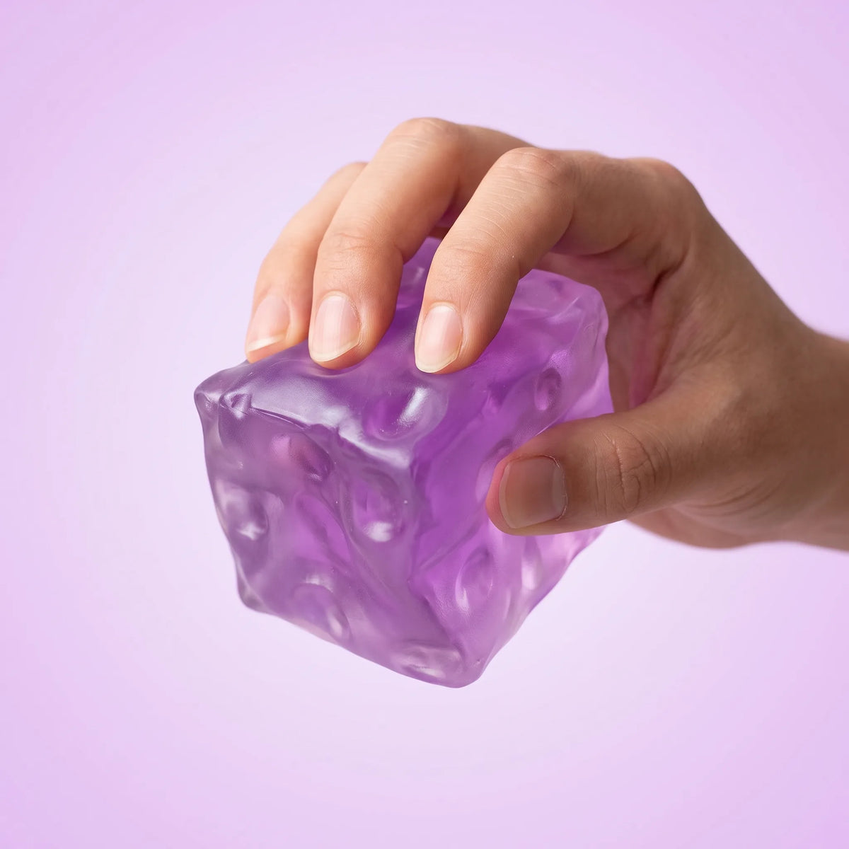 Hand squeezing the clear purple cheese squishy cube