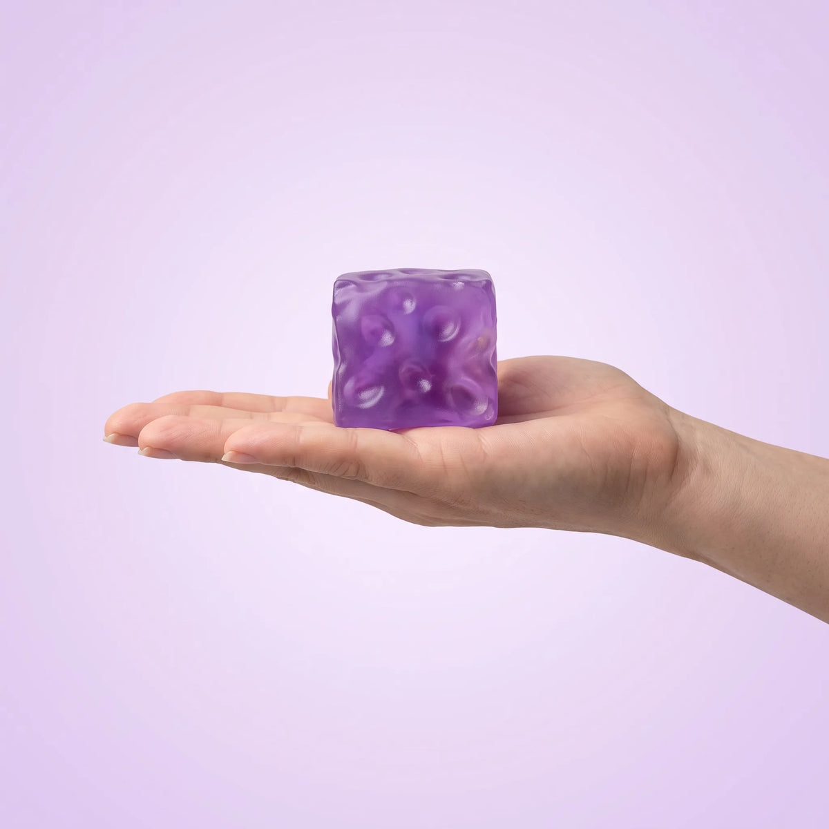 Clear purple cheese squishy cube held in an open hand at 7 cm