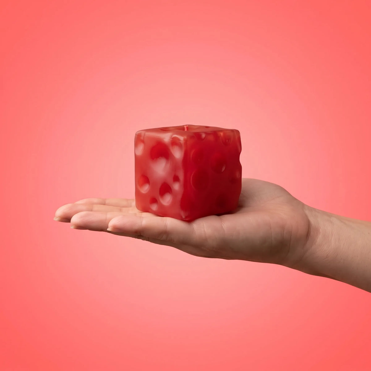 Clear red cheese squishy cube filling an open palm at 7 cm