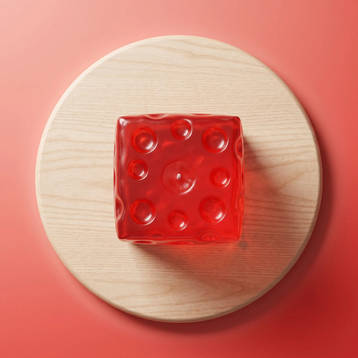 Clear red cheese squishy cube resting on a round wooden board