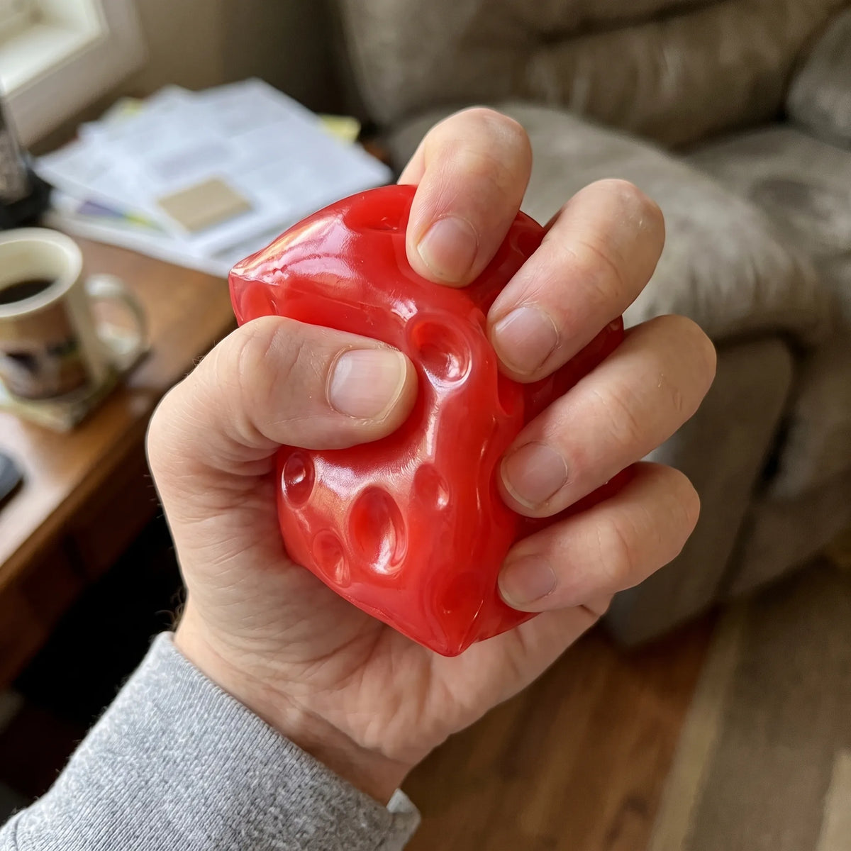 Adult hand pressing the clear red cheese squishy cube flat