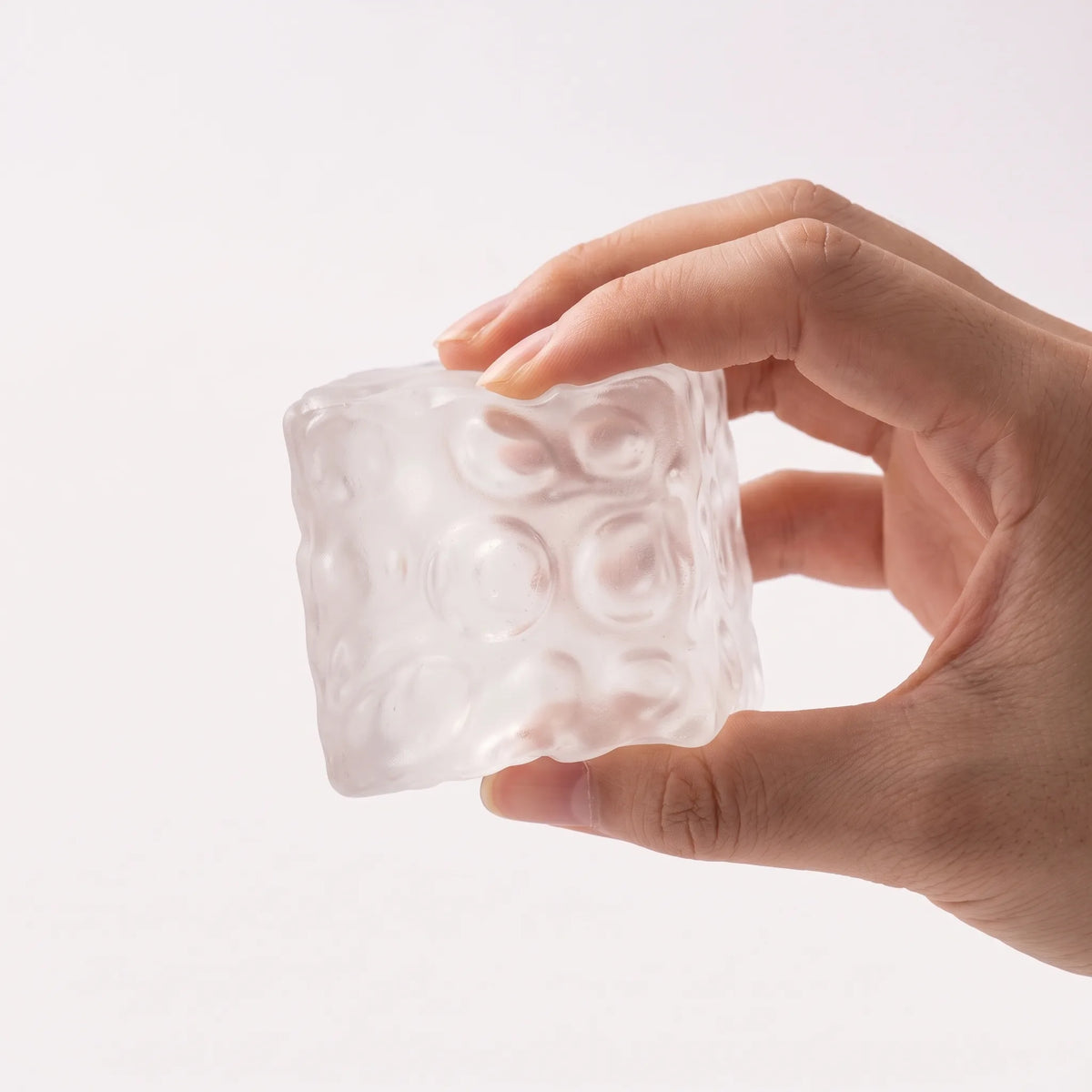 Fingers squeezing the clear white cheese squishy cube