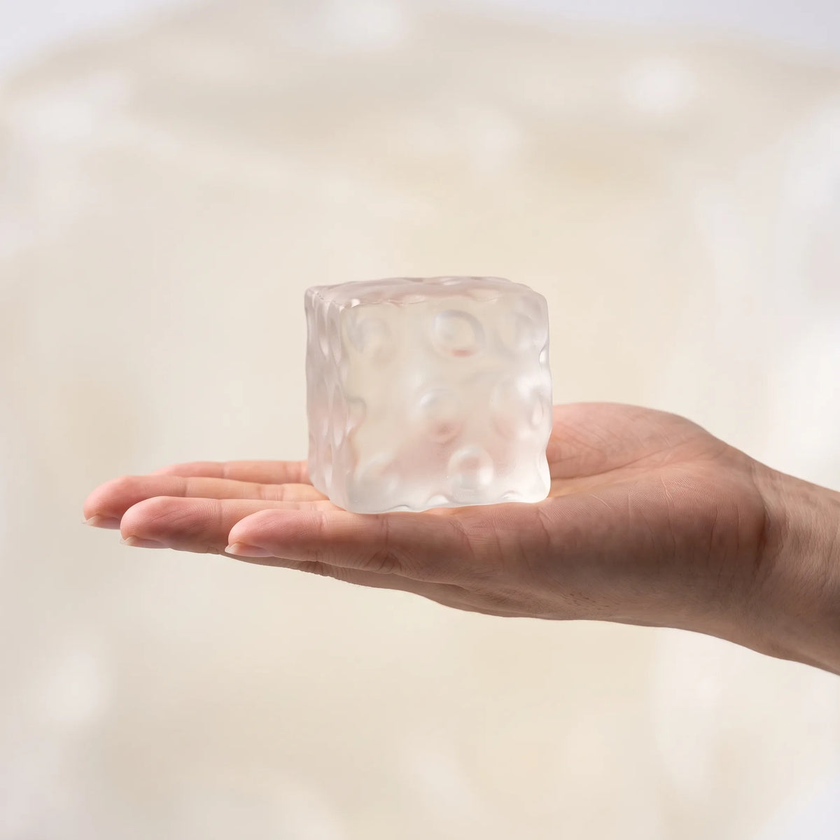 Clear cheese squishy cube held in an open hand to show its size