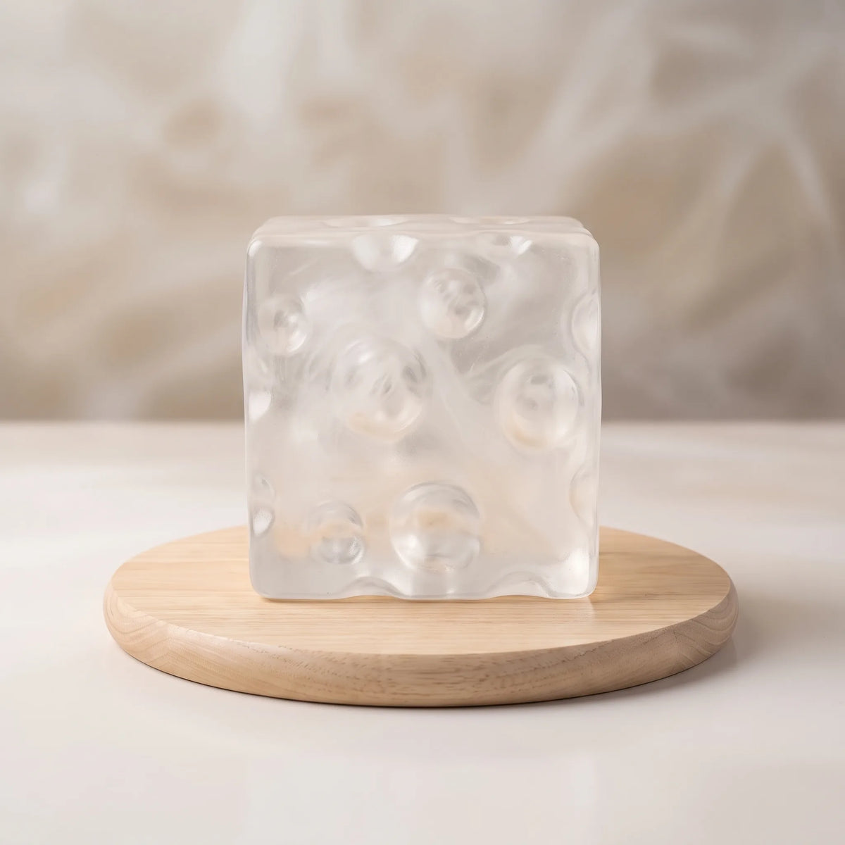 Clear white cheese squishy cube resting on a round wooden board