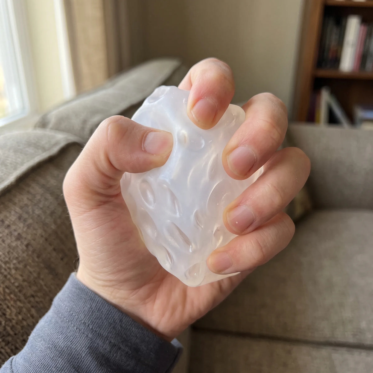 Adult hand pressing the clear white cheese squishy cube flat