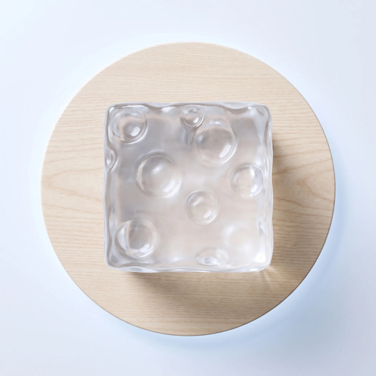 Colourless cheese squishy cube photographed against a pale backdrop
