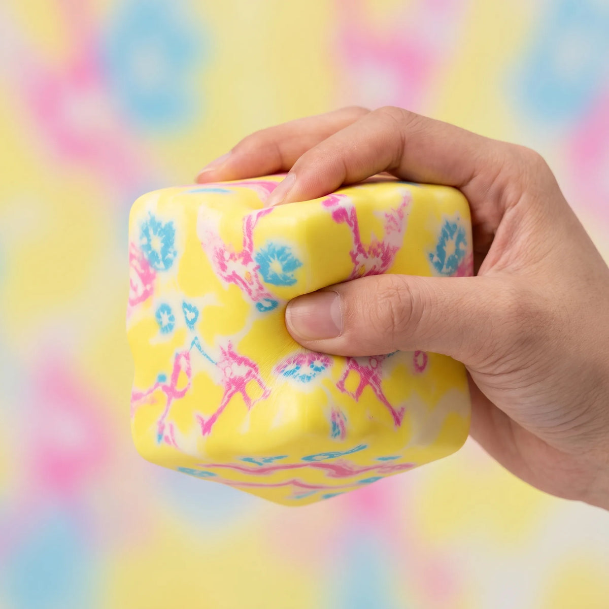 Hand squeezing the flower yellow cheese squishy block