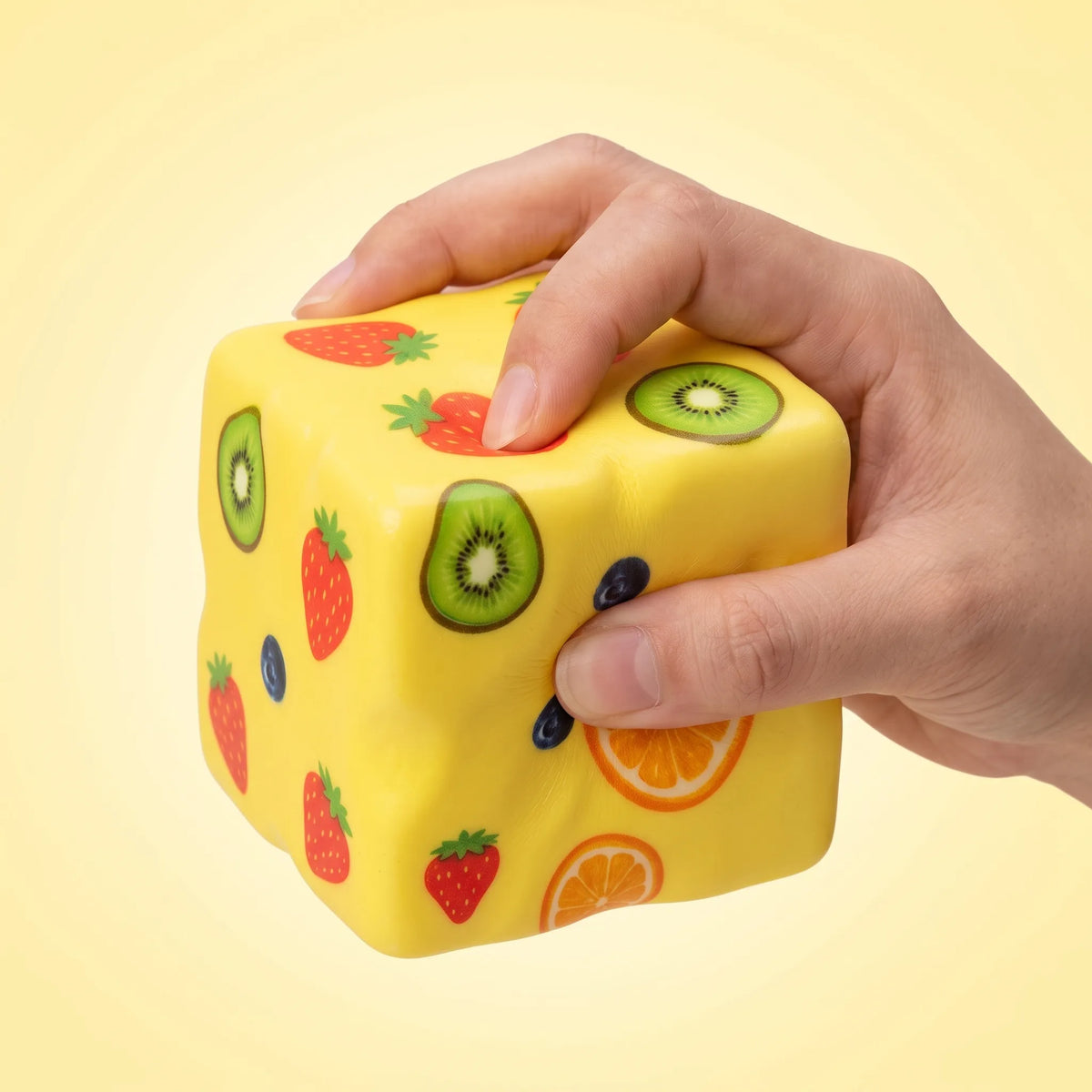 Hand squeezing the fruit-print cheese squishy block