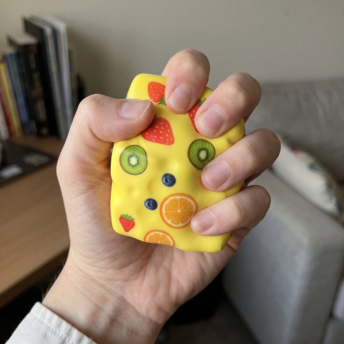 Adult hand pressing the fruit cheese squishy block flat