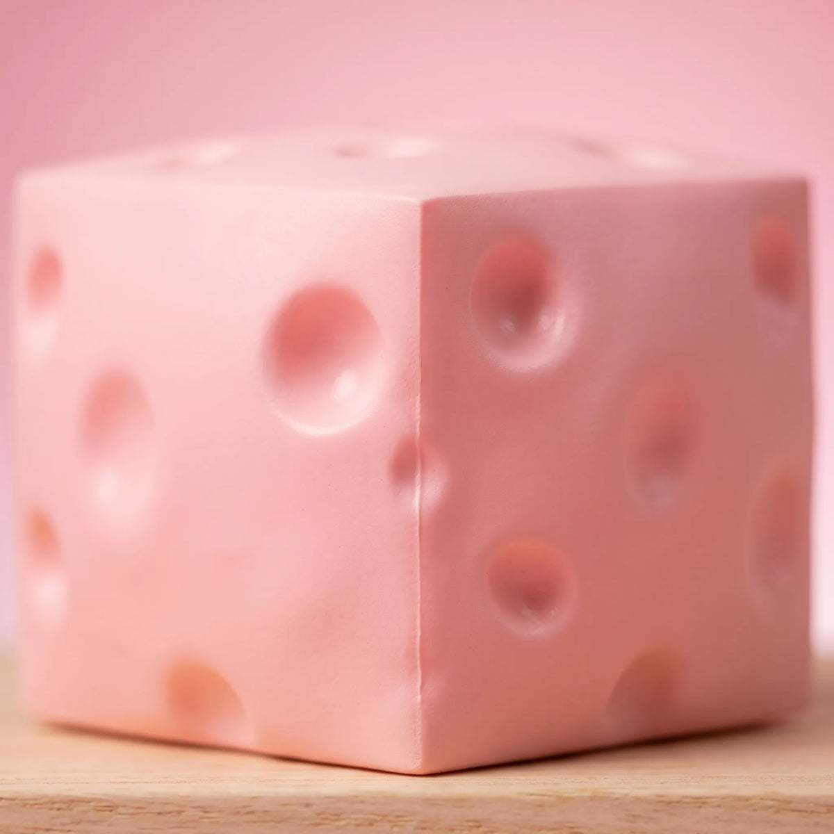 Macro view of the moulded holes and matte surface of the pink cheese squishy block