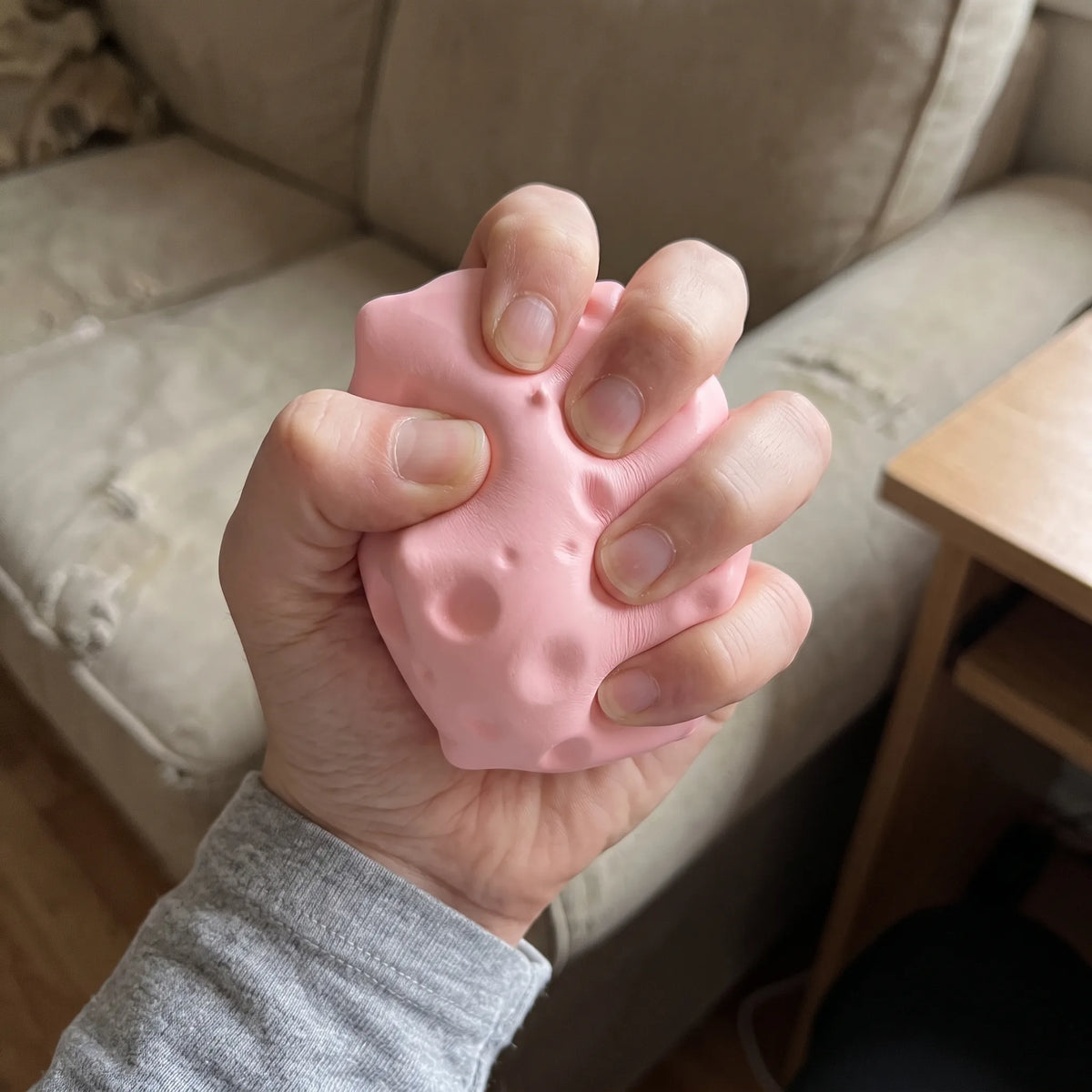 Adult hand pressing the pink cheese squishy block flat