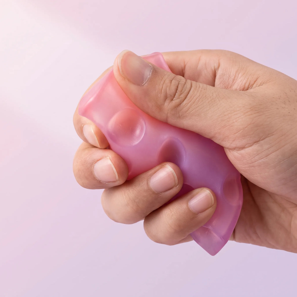 Fingers squeezing the pink cheese squishy wedge until it folds