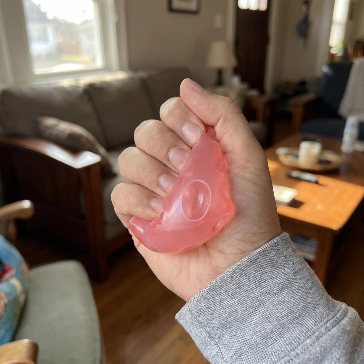 Adult hand pressing the pink cheese squishy wedge flat