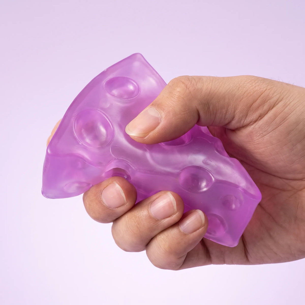 Fingers squeezing the purple cheese squishy wedge so the thin point folds first