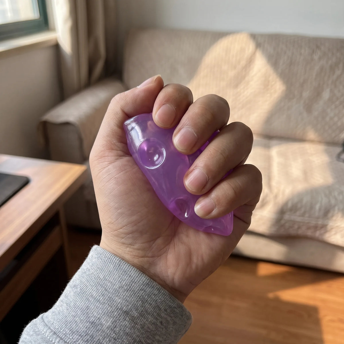 Adult hand pressing the purple cheese squishy wedge flat