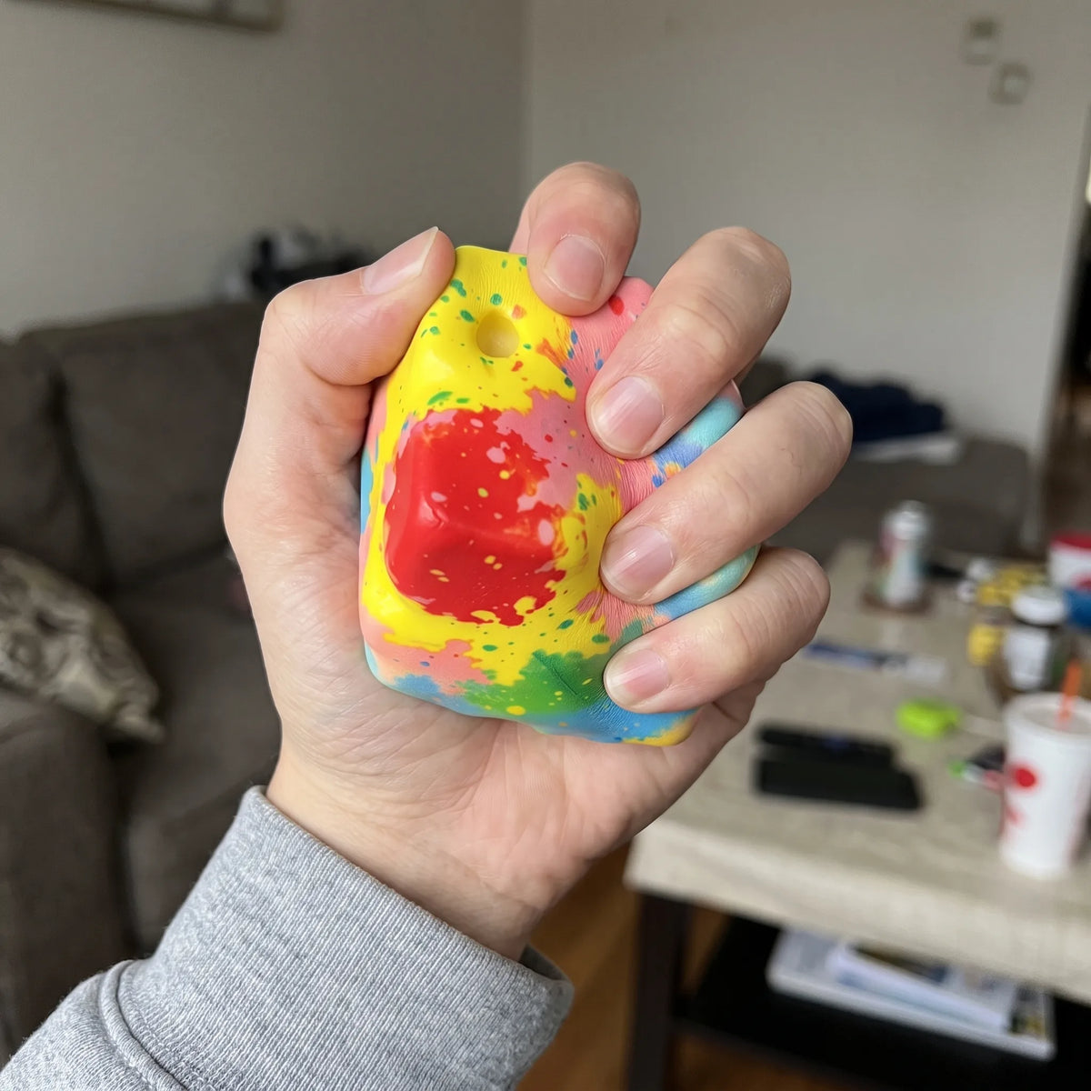 Adult hand pressing the rainbow cheese squishy block flat