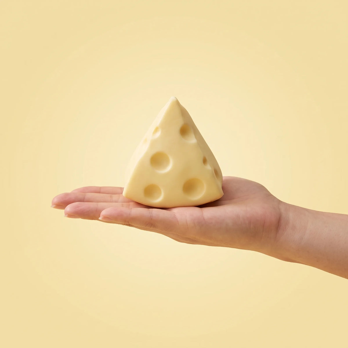 Cheese squishy triangle held in an open hand to show its 6 cm size