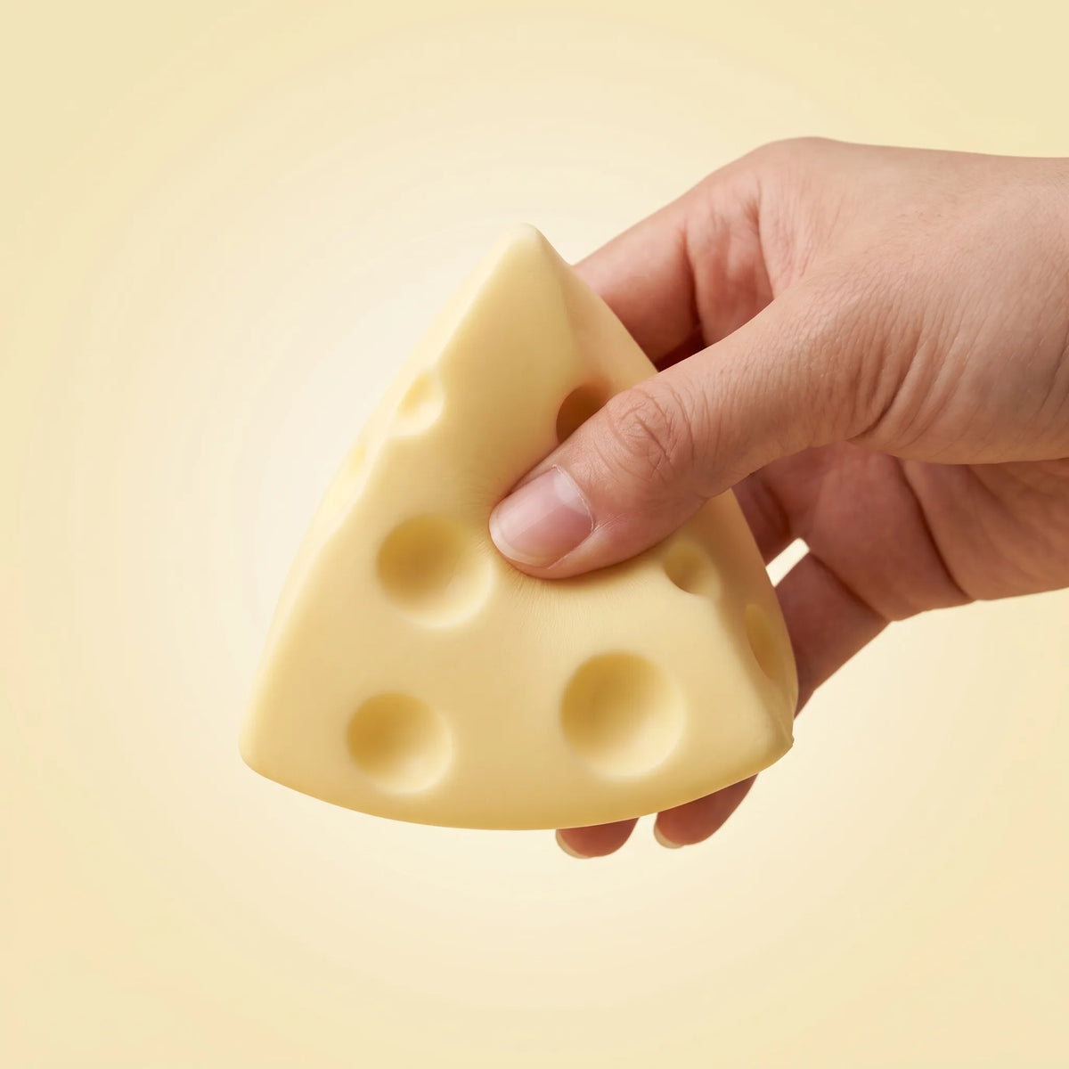 Fingers pressing the point of the cheese squishy triangle