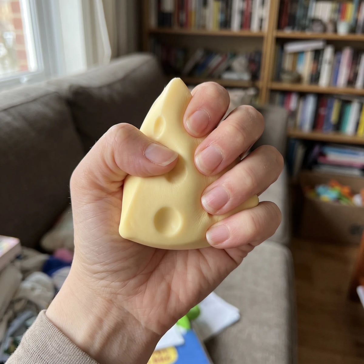 Hand squeezing the Swiss cheese squishy triangle flat